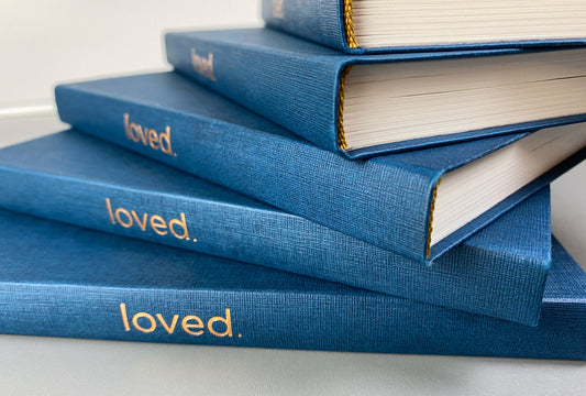 Stack of high quality Loved journals displaying the spines and sewn binding. Over 100 lined and framed pages for messages with facing pages left blank for drawings, overflow messages, or space between messages..